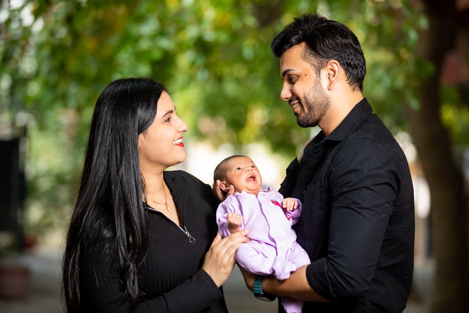 Happy family holding their newborn baby outdoors, filled with love and smiles.